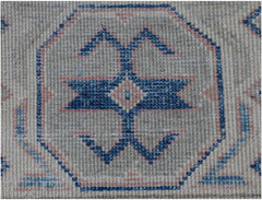 A handmade Afghan Kazakh rug featuring a central blue geometric motif on a light textured background.