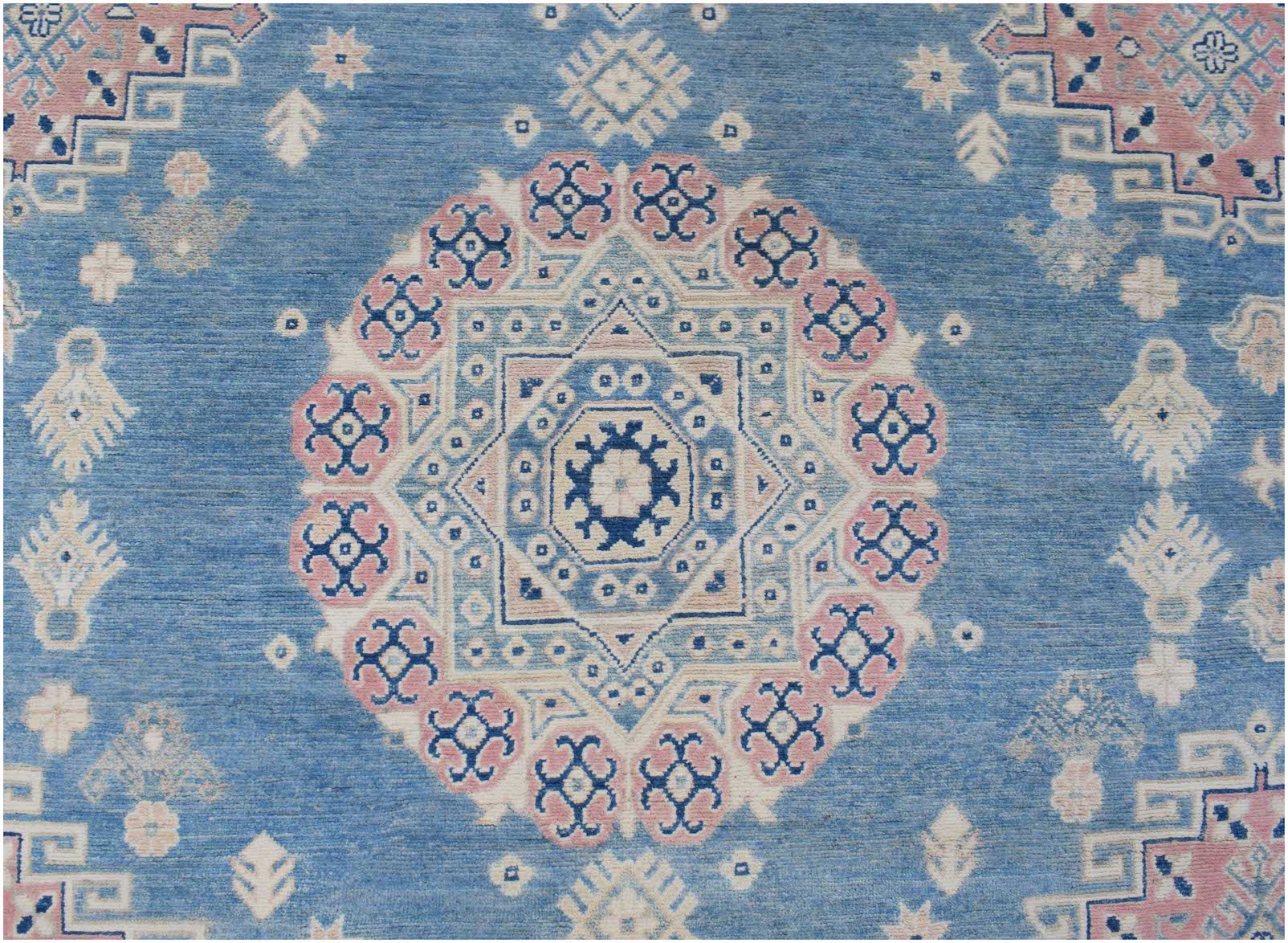 Handmade Afghan Kazakh rug featuring a central geometric medallion in blue, pink, and cream.