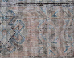 A handmade Afghan Kazakh rug featuring traditional floral patterns in muted blue and brown tones.