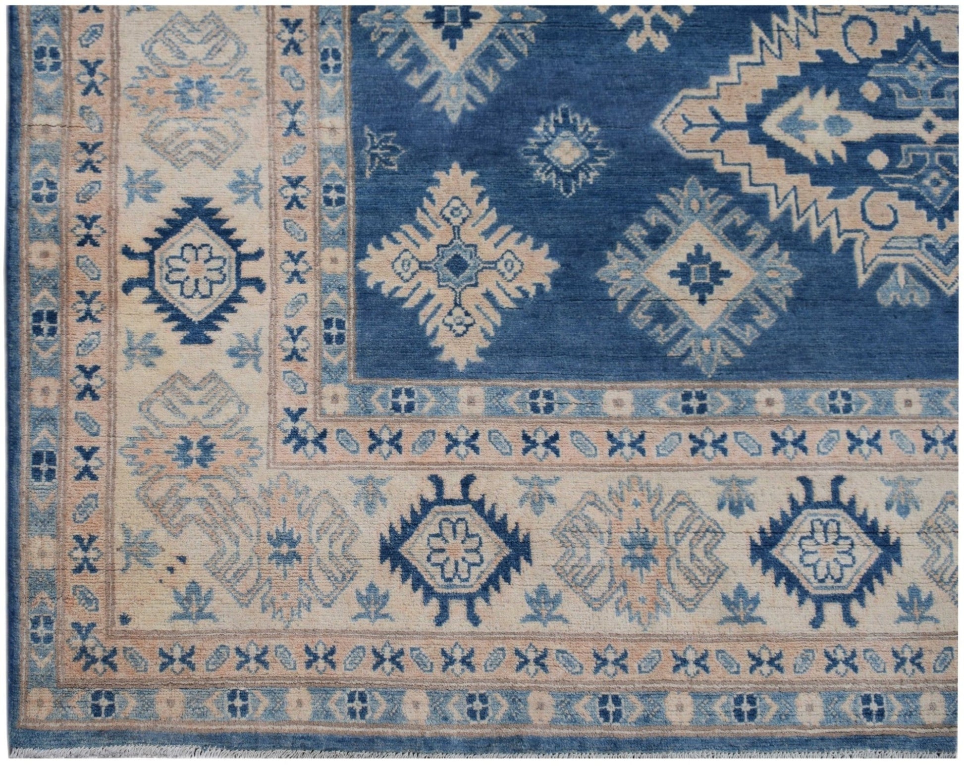 Handmade Afghan Kazakh rug featuring a blue field with beige geometric patterns and a wide border.