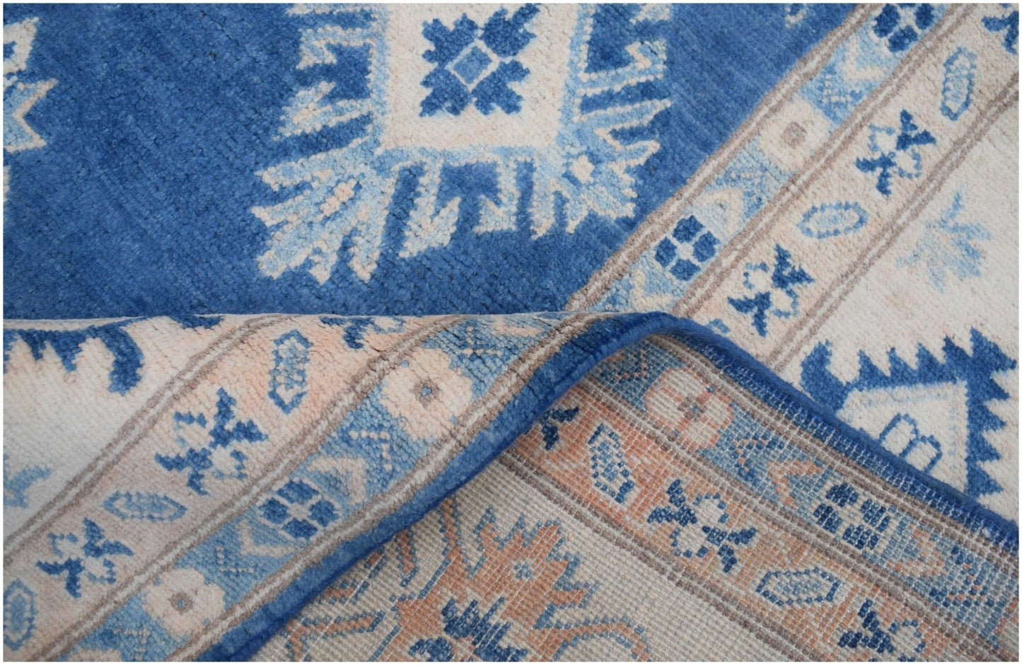A handmade Afghan Kazakh wool rug featuring a geometric pattern in shades of blue and beige.