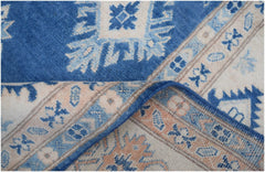 A handmade Afghan Kazakh wool rug featuring a geometric pattern in shades of blue and beige.