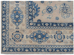 An Afghan Kazakh rug featuring a beige field with blue floral motifs and a geometric border.