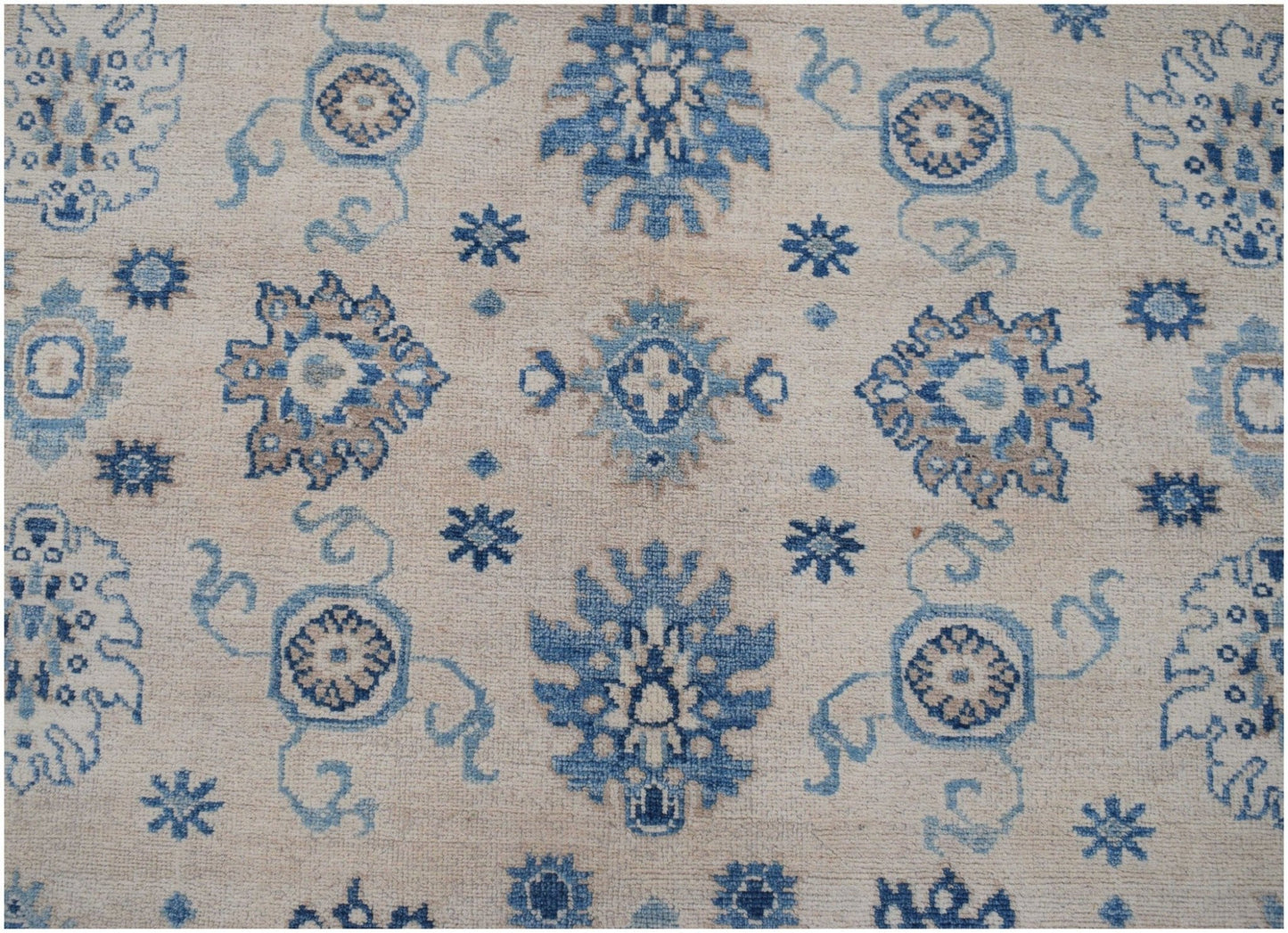 Handmade Afghan Kazakh rug featuring a beige background with blue and grey floral motifs.