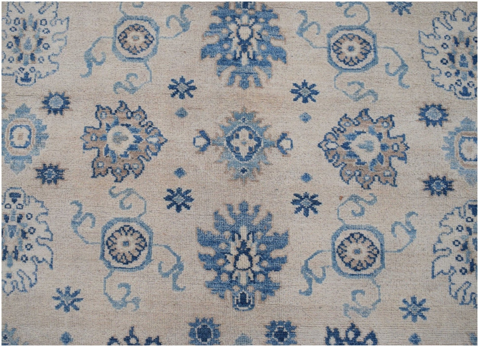 Handmade Afghan Kazakh rug featuring a beige background with blue and grey floral motifs.