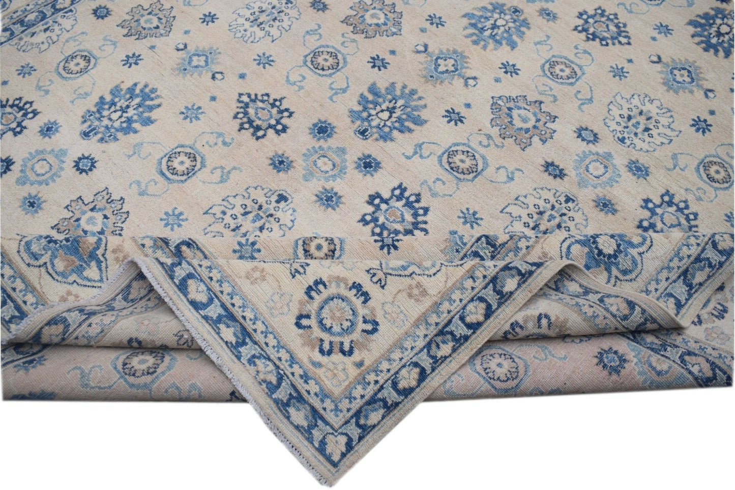 Handmade Afghan Kazakh wool rug featuring a beige field with blue and grey floral motifs.