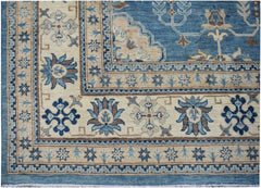 A handmade Afghan Kazakh rug featuring a blue and beige floral pattern with a geometric border.
