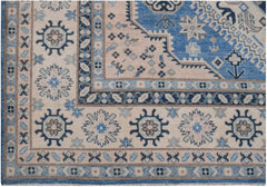 Handmade Afghan Kazakh rug featuring a geometric floral pattern in shades of blue, beige, and grey.