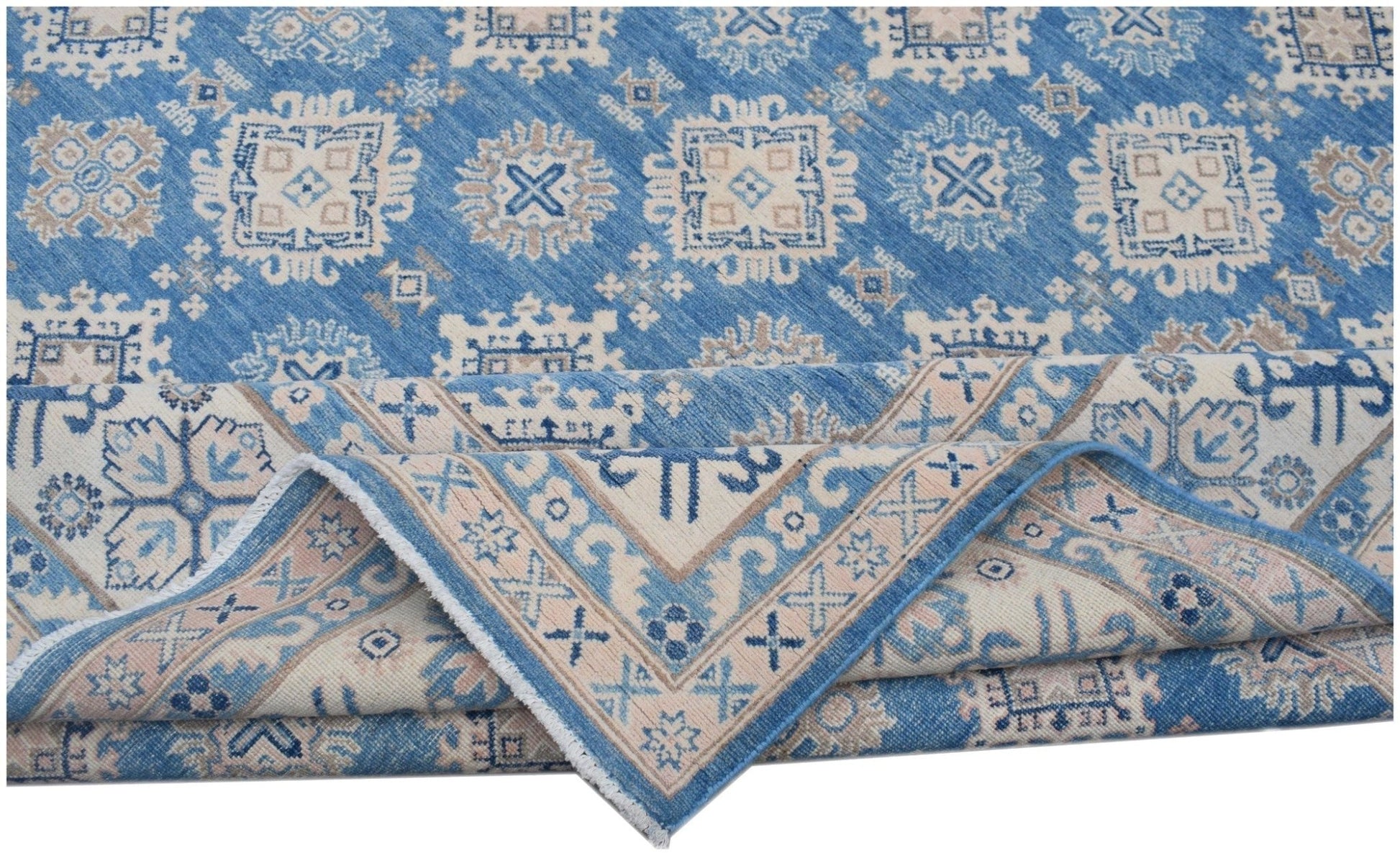 A handmade Afghan Kazakh rug featuring a blue field with beige geometric patterns and a folded edge.