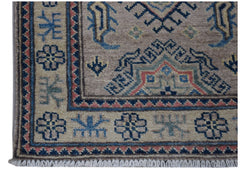 A handmade Afghan Kazakh runner featuring traditional geometric motifs in blue, red, and tan wool.