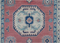 Handmade Afghan Kazakh runner rug featuring a central geometric medallion on a pink wool field.