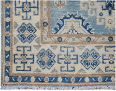 Handmade Afghan Kazakh runner rug featuring geometric blue and beige patterns on a cream field.