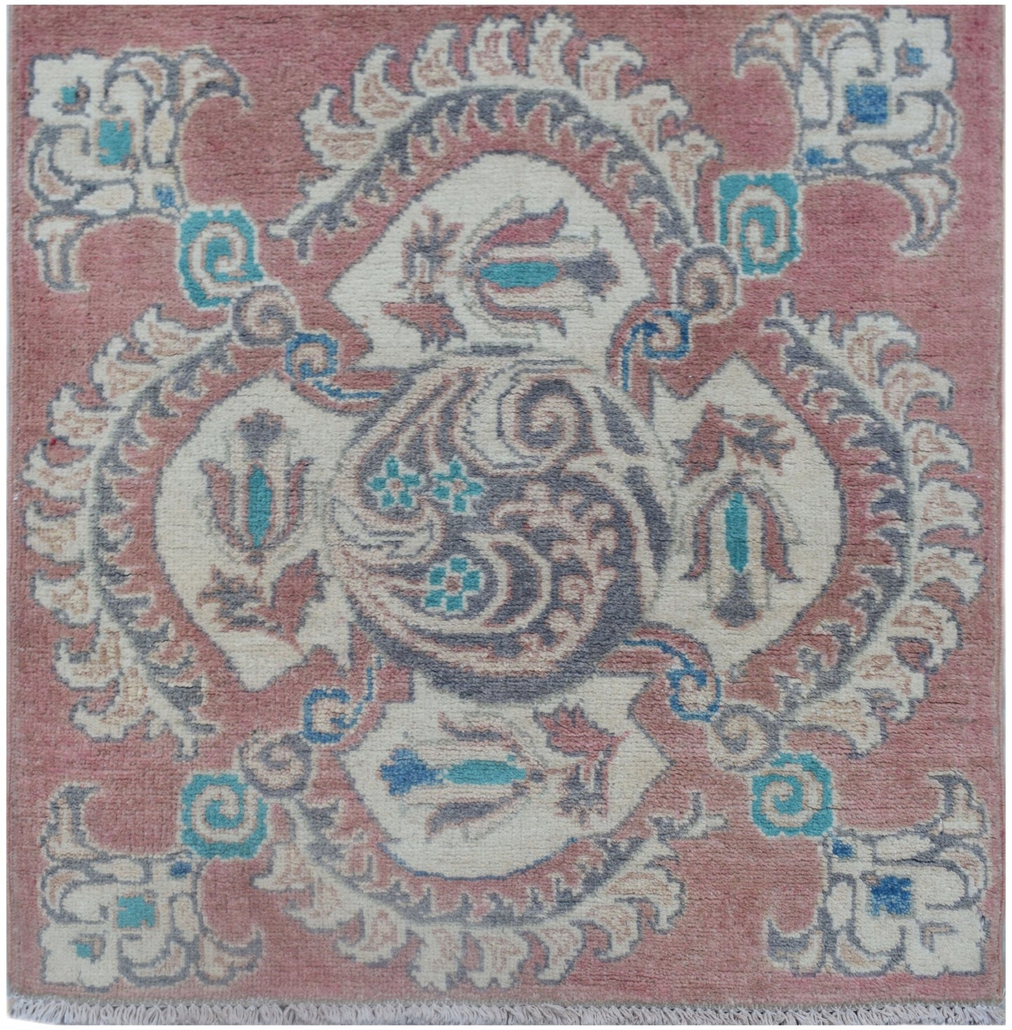 A square Afghan Kazakh rug featuring a central floral medallion in pink, cream, and blue tones.