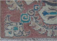 A handmade Afghan Kazakh runner featuring traditional floral motifs in pink, blue, and cream wool.