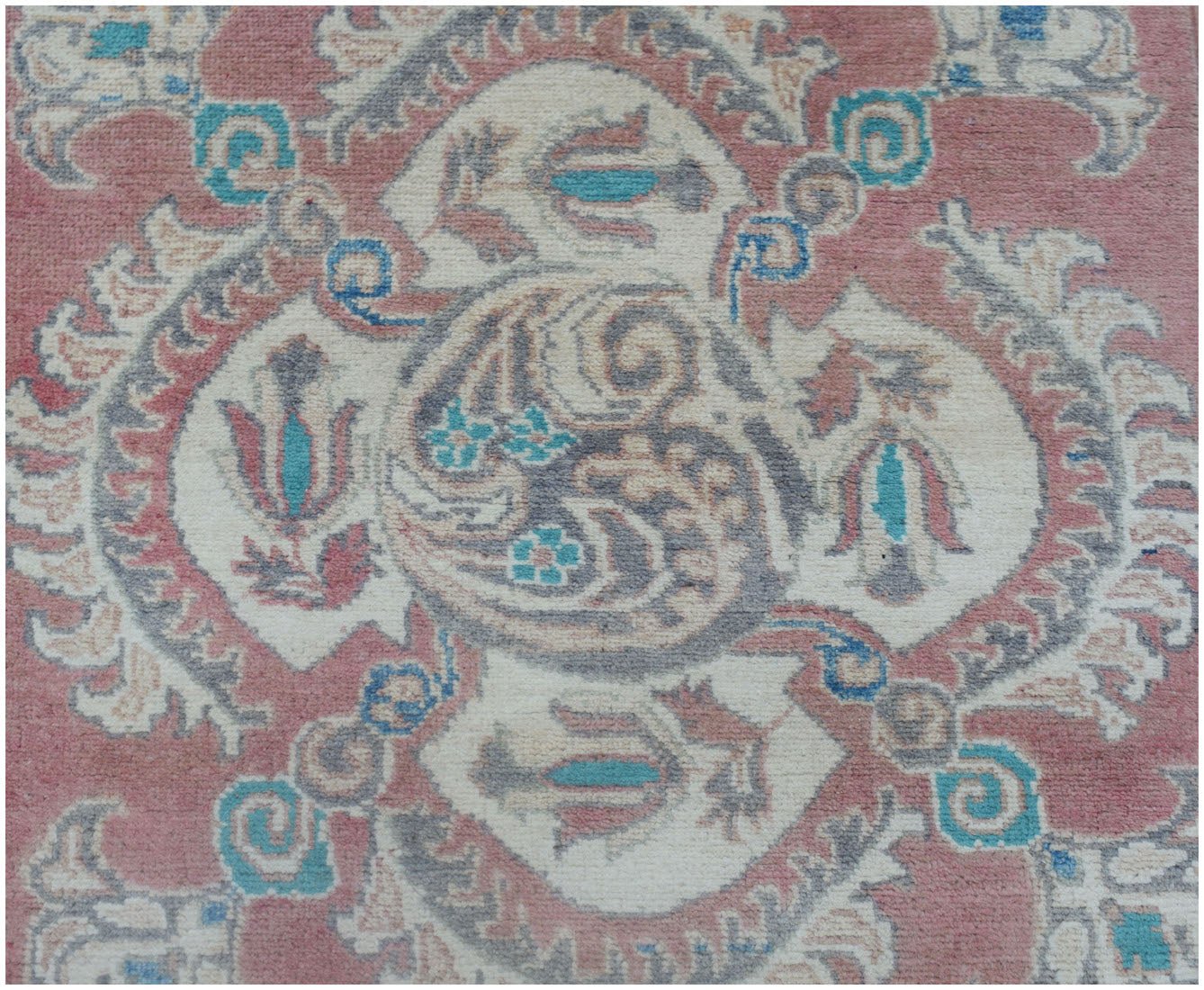 A handmade Afghan Kazakh runner featuring traditional floral motifs in pink, blue, and cream.