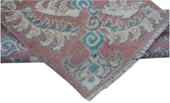 A handmade Afghan Kazakh runner featuring traditional motifs in pink, cream, and blue wool.