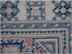 A handmade Afghan Kazakh runner featuring traditional geometric motifs in blue, pink, and cream.