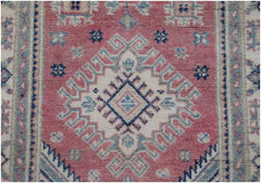 Handmade Afghan Kazakh runner rug featuring a geometric diamond pattern in pink, blue, and cream.