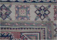 A close-up of an Afghan Kazakh runner featuring traditional geometric motifs in blue and pink.