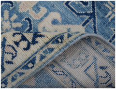 A handmade Afghan Kazakh runner rug featuring a blue and beige geometric pattern.