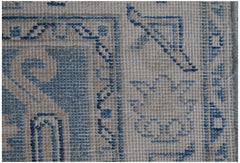 A close-up view of an Afghan Kazakh runner rug featuring blue geometric patterns on a beige base.
