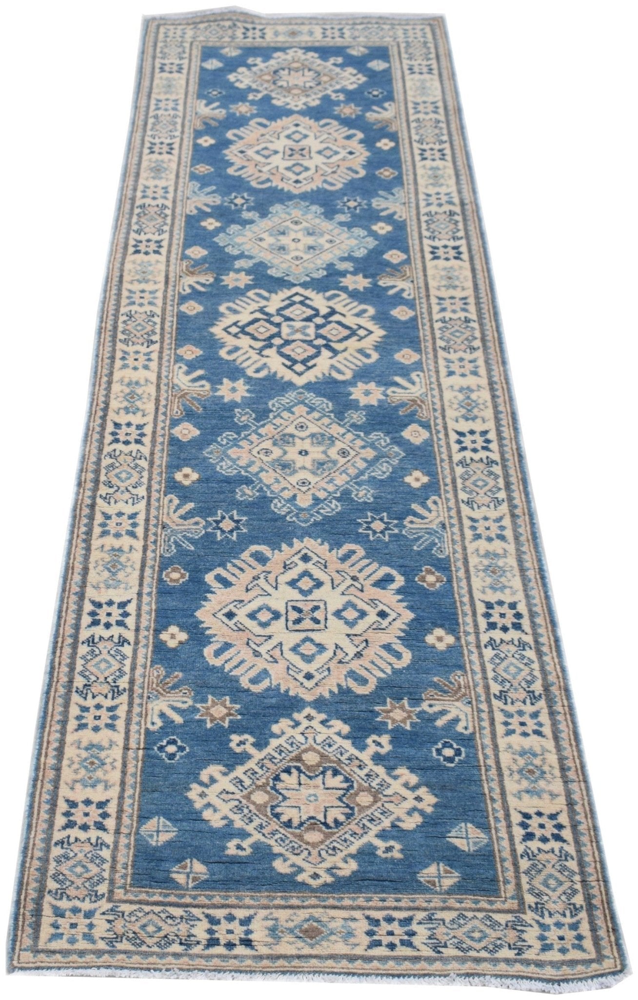 A handmade Afghan Kazakh runner rug featuring a blue field with repeating beige and grey geometric medallions.