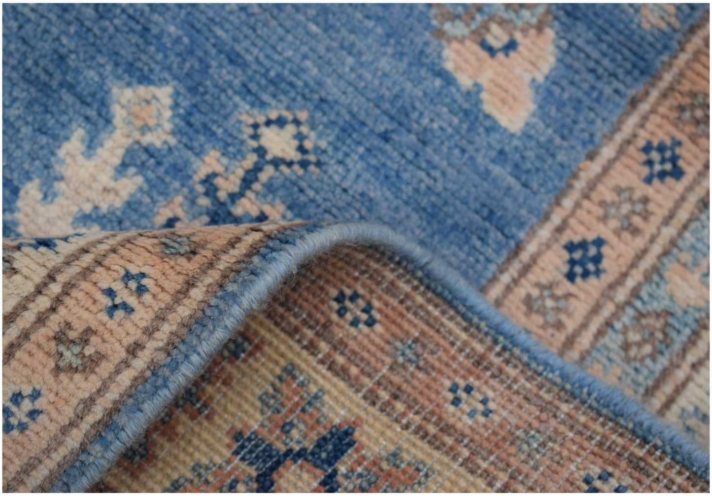 A close-up of a handmade Afghan Kazakh runner rug featuring blue and beige geometric patterns.