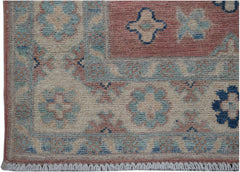 A handmade Afghan Kazakh runner featuring traditional floral motifs in blue, pink, and cream wool.
