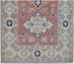 Handmade Afghan Kazakh runner featuring a central geometric medallion on a dusty pink field.