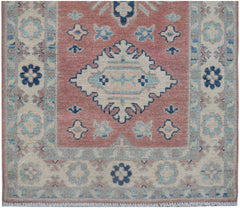 Handmade Afghan Kazakh runner featuring a central medallion on a dusty rose field with floral motifs.