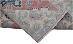 A handmade Afghan Kazakh runner featuring traditional floral motifs in pink, blue, and cream wool.