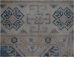 A handmade Afghan Kazakh runner featuring a beige wool base with intricate blue geometric patterns.