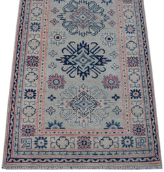 Handmade Afghan Kazakh runner rug featuring traditional geometric motifs in blue and pink.