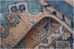 A close-up view of a handmade Afghan Kazakh runner featuring intricate blue and beige patterns.