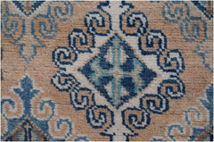 A close-up of an Afghan Kazakh runner rug featuring a blue and beige geometric diamond pattern.