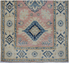 Handmade Afghan Kazakh runner featuring a central blue diamond motif on a soft pink field.