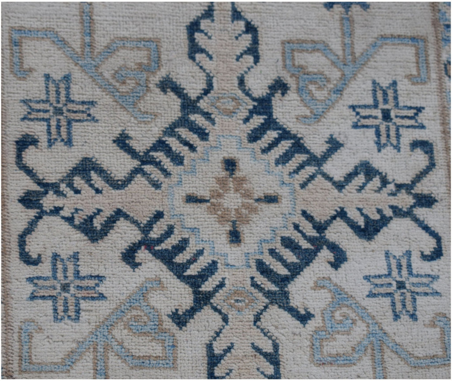 A handmade Afghan Kazakh runner featuring a geometric blue and beige pattern on a cream background.