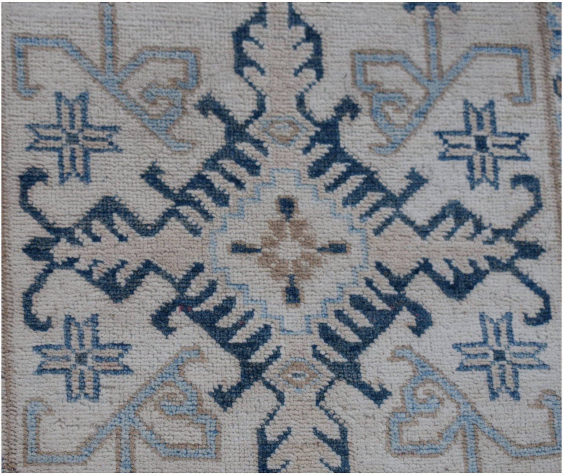 A handmade Afghan Kazakh runner featuring a geometric blue and beige pattern on a cream background.