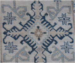 A handmade Afghan Kazakh runner featuring a geometric blue and beige pattern on a cream background.