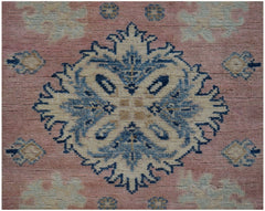 A handmade Afghan Kazakh runner featuring a central blue and beige floral medallion on a pink field.