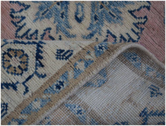 A handmade Afghan Kazakh runner featuring a beige, blue, and pink geometric pattern.