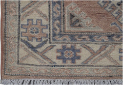 A handmade Afghan Kazakh runner featuring traditional geometric motifs in muted blue and tan wool.