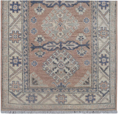 An Afghan Kazakh runner rug featuring traditional geometric motifs in muted pink and blue tones.