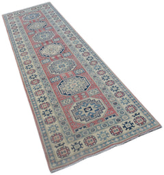 A handmade Afghan Kazakh runner rug featuring traditional geometric motifs in pink and blue.
