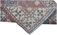 A handmade Afghan Kazakh runner featuring traditional geometric motifs in pink, blue, and cream.