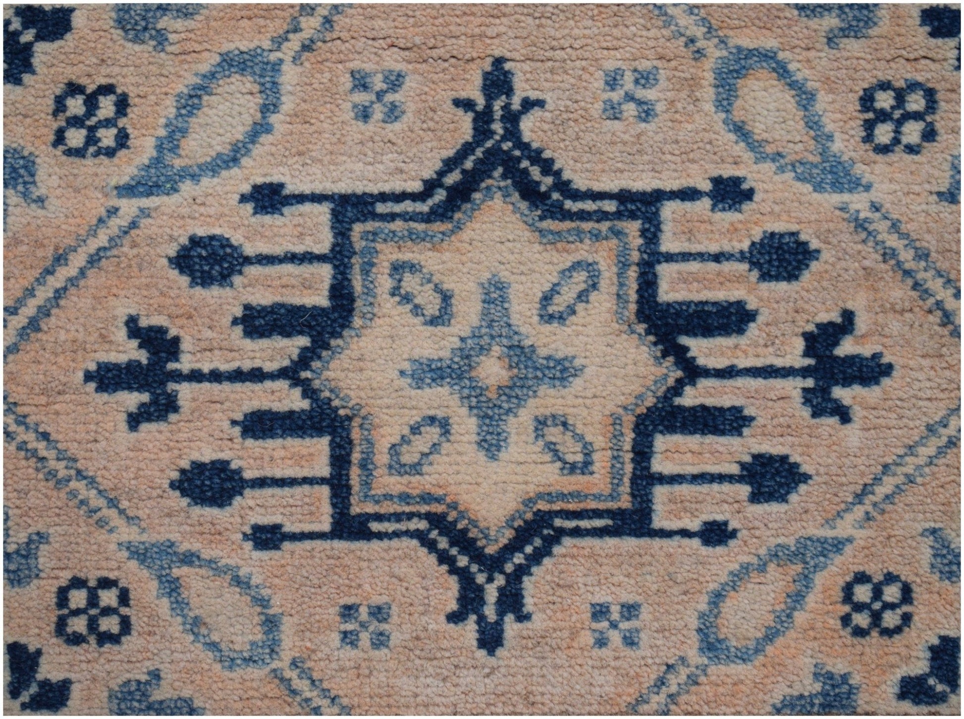 Handmade Afghan Kazakh runner featuring a central blue geometric medallion on a beige wool field.