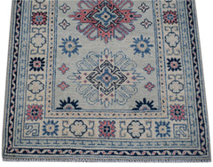 Handmade Afghan Kazakh runner rug featuring traditional geometric motifs in blue and pink.