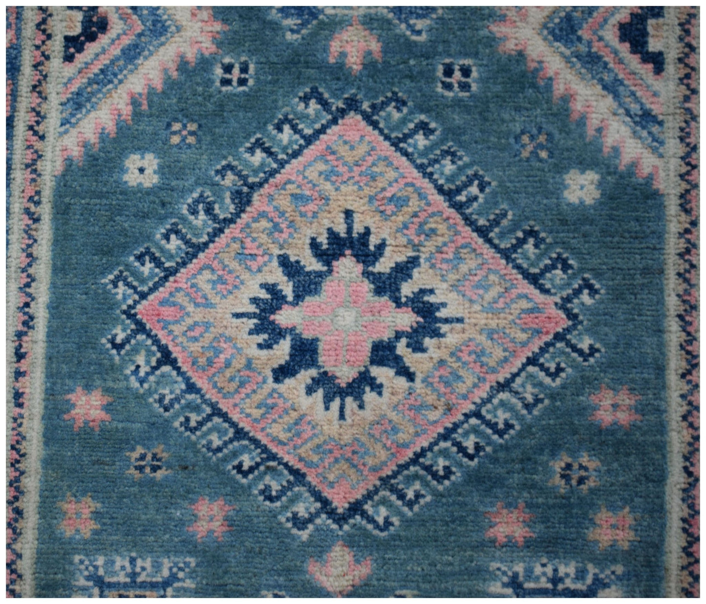 A handmade Afghan Kazakh runner featuring a central diamond medallion in blue, pink, and cream.