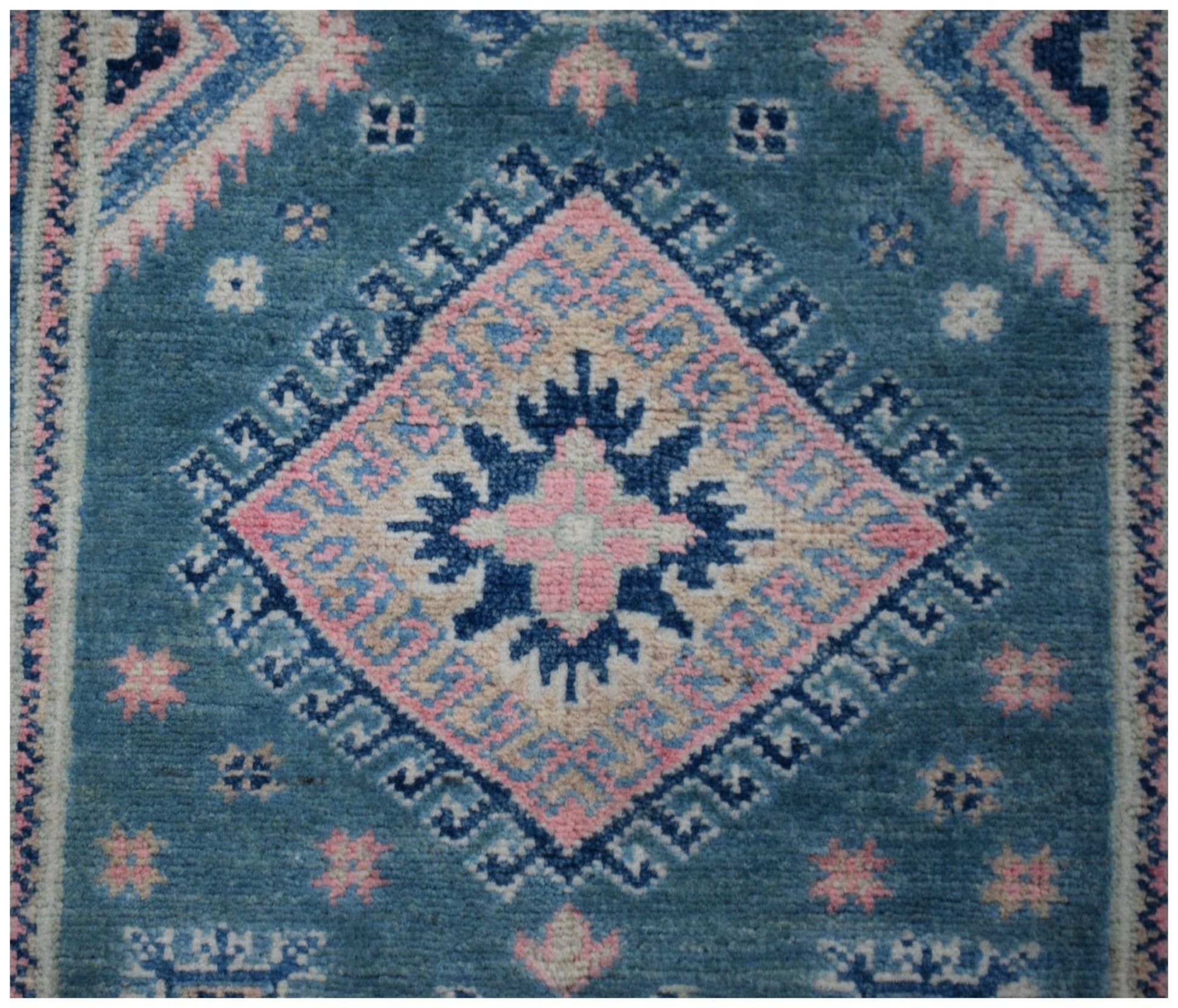 A handmade Afghan Kazakh runner featuring a central diamond medallion in blue, pink, and cream.