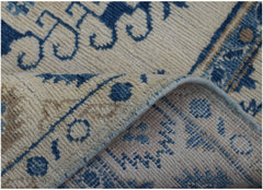 A corner of a handmade Afghan Kazakh runner featuring blue traditional patterns on a cream background.